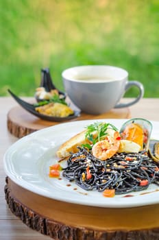 close up black seafood pasta on white plate