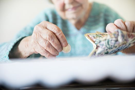 Detailed closeup photo of elderly 96 years old womans hands counting remaining coins from pension in her wallet after paying bills. Unsustainability of social transfers and pension system.