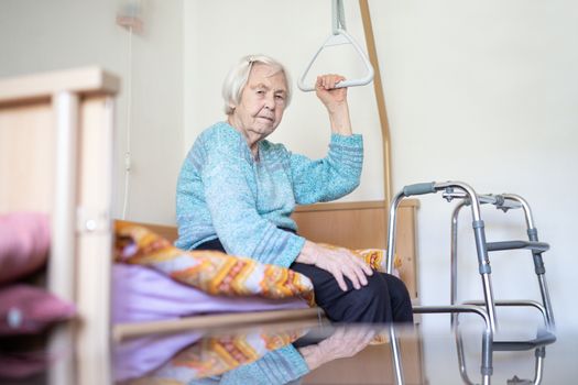 Elderly 96 years old woman sitting on medical bed in hospic. Palliative health care support for older people concept. Care for the elderly.