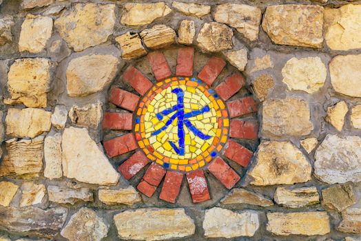 Circular mosaic religious symbol of confucianism on stone wall.