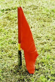 red flag stick on grassland.