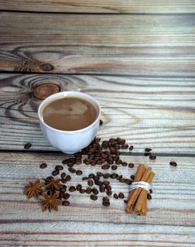 Still life on a wooden table, a cup of cappuccino, cinnamon, star anise and coffee beans.