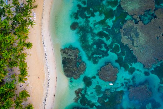 Drone shot of tropical beach with white boat anchored.Samana peninsula,Grand Bahia Principe El Portillo beach,Dominican Republic.