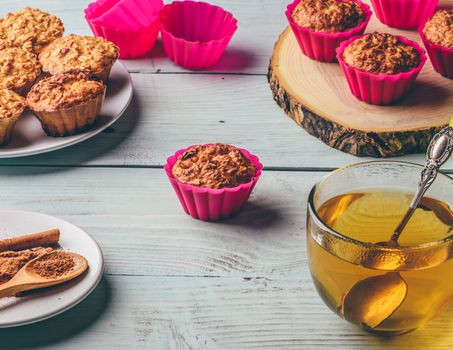 Healthy Dessert. Oatmeal muffins with cup of green tea over light wooden background.