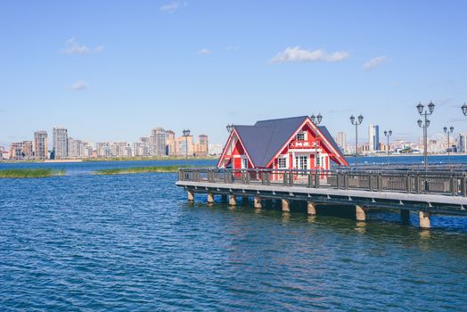 Little red house on pier. High-rises buildings on background.