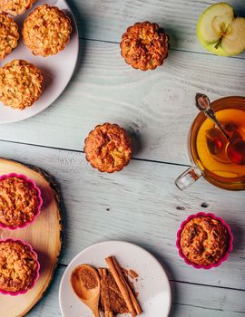 Healthy Breakfast. Cooked oatmeal muffins with apple and cup of green tea over light wooden background. View from above.