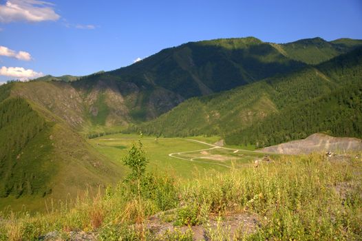 Pasture and fertile valley sandwiched in the mountains. Altai, Siberia, Russia.