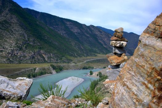 Socral pyramid on the top of the mountain, against the background of the bend of the turquoise Katun River. Altai, Siberia, Russia.