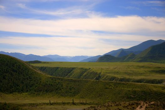 Pasture and fertile valley sandwiched in the mountains. Altai, Siberia, Russia.