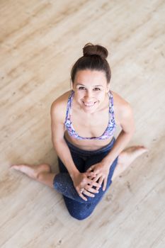 Cheerful fit sporty active girl in fashion sportswear sitting on the floor in yoga studio. Active urban lifestyle.