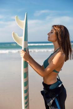 Beautiful surfer girl at the beach holding a surfboard 