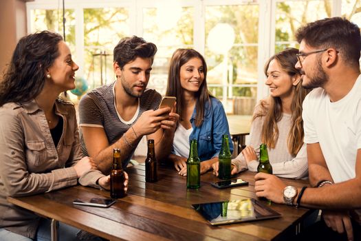 A group of friends at the bar drinking a beer 