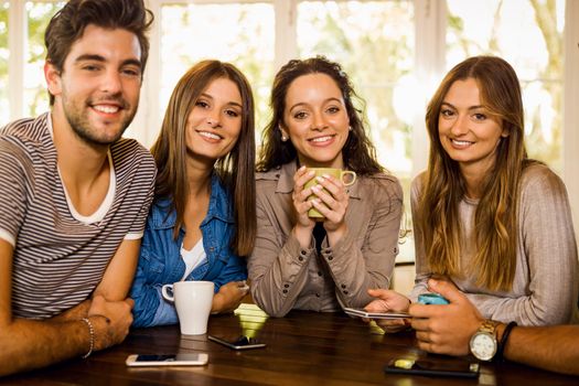 A group of friends looking to the camera and drinking coffee at the cafe