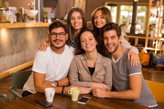 A group of friends looking to the camera at the cafe 