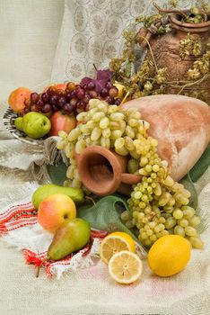 Old ceramic vase, pot and fruits on a fabric background