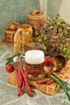 Mug of bier, sausages and greenery on a canvas background