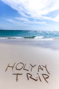 Holiday trip handwriting on tropical sea beach