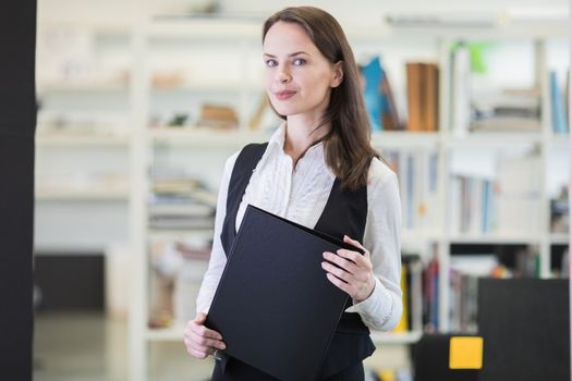 Business woman standing in office holding folder of files