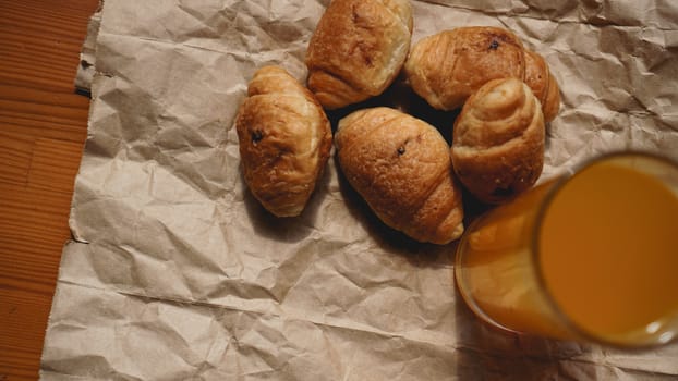 Freshly baked croissants with orange juice on kraft paper. Closeup photography of fresh delicious dessert for breakfast.