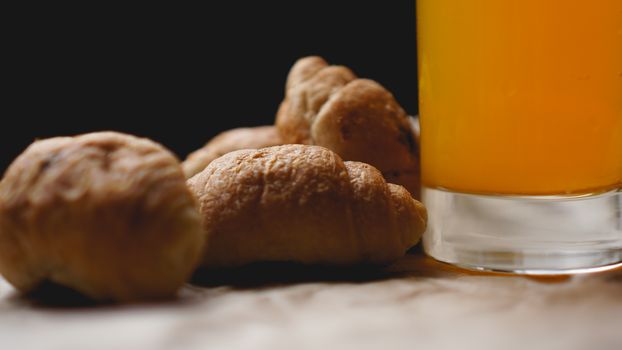 Freshly baked croissants with orange juice on kraft paper. Closeup photography of fresh delicious dessert for breakfast.