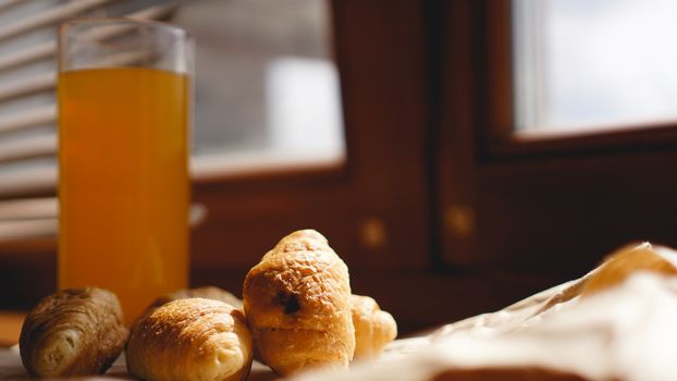 Freshly baked croissants with orange juice on kraft paper. Closeup photography of fresh delicious dessert for breakfast.