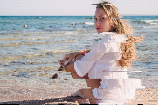 A young blonde girl in a white shirt pensive sits on the beach in Egypt. Exotic beauty. A high resolution. Glitch vintage shabby coral turquoise effect.