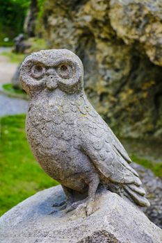 Old owl sculpture on stone in a park or garden