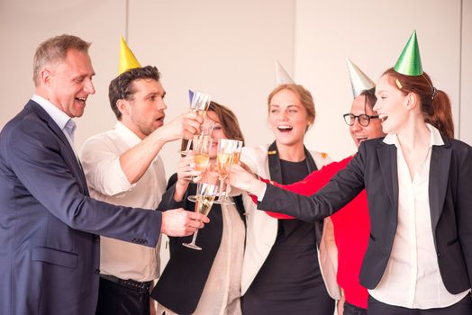 People in business outfit celebrating something in the office clinking glasses of champagne