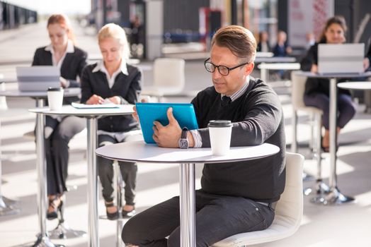 Many business people sitting in cafe , focus on man with tablet pc