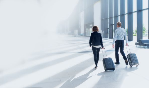 Businessman and businesswoman walking with luggage suitcases, travel to business trip