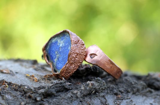 a Hand made copper ring with blue semiprecious stone on the wooden background