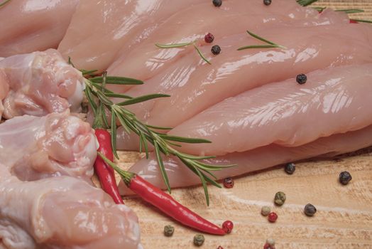 .Raw chicken meat on wooden board. Healthy eating.Raw, fresh chicken meat platter on a wooden surface with spices for cooking.