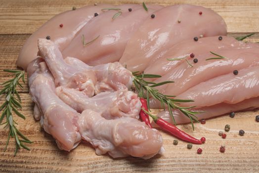 .Raw chicken meat on wooden board. Healthy eating.Raw, fresh chicken meat platter on a wooden surface with spices for cooking.