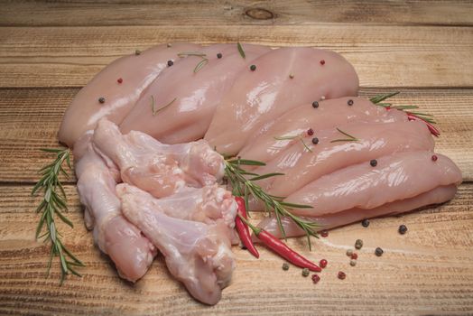 .Raw chicken meat on wooden board. Healthy eating.Raw, fresh chicken meat platter on a wooden surface with spices for cooking.