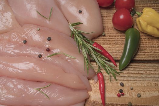 .Raw chicken meat on wooden board. Healthy eating.Raw, fresh chicken meat platter on a wooden surface with spices for cooking.