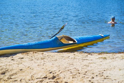 Kayak on the beach. Kayak blue and yellow. Boat on the river bank. Summer sunny day. Kayak sport.Kayaking concept.