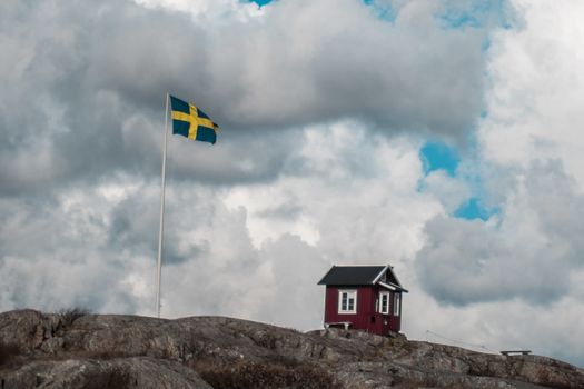 A classic red hut in Sweden next to a Swedish flag