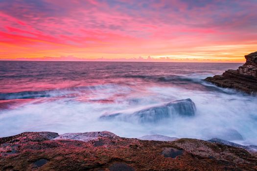 Blazing red pink orange and yellow sunrise skies over the east Sydney coastline