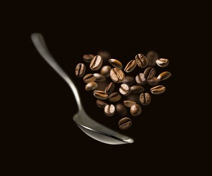 Coffee beans in the shape of a heart and a spoon in flight.