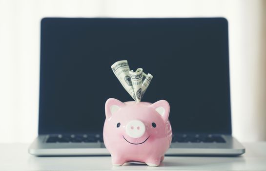 piggy bank with laptop on the desk, online shopping concept