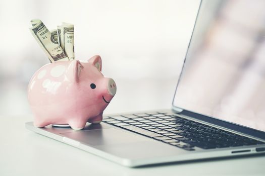 piggy bank with laptop on the desk, online shopping concept