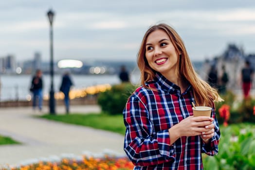 Coffee on the go. Beautiful young woman holding coffee cup and smiling