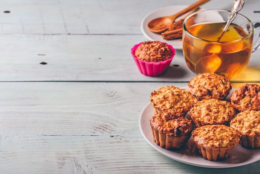 Healthy Dessert. Oatmeal muffins with cup of green tea over light wooden background. Copy Space.