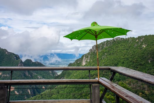 The viewpoint on the mountain has a green umbrella. There are spots for tourists to sit and watch the beauty of the mountains.