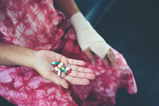 Senior asian woman take pill medicine on hand while sitting on sofa at home 