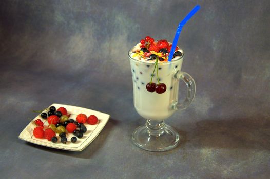 Milkshake with a glass glass with a straw and wild berries.