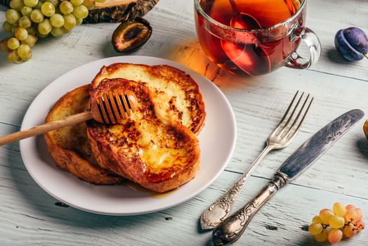 Healthy breakfast concept. French toasts with honey, fruits and tea over white wooden background