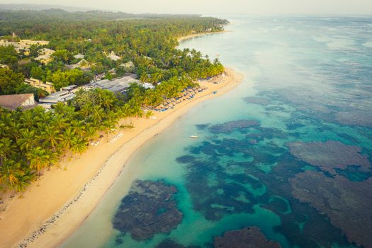 Drone shot of tropical beach with white boat anchored.Samana peninsula,Bahia Principe beach,Dominican Republic.