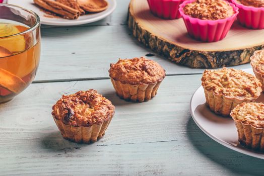 Healthy Dessert. Oatmeal muffins with cup of green tea over light wooden background.