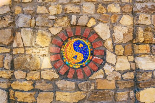 Circular mosaic religious symbol of Yin and yang on stone wall.